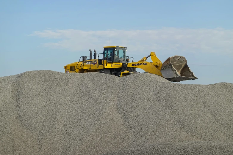 a bulldozer scoops dirt up onto a large mound