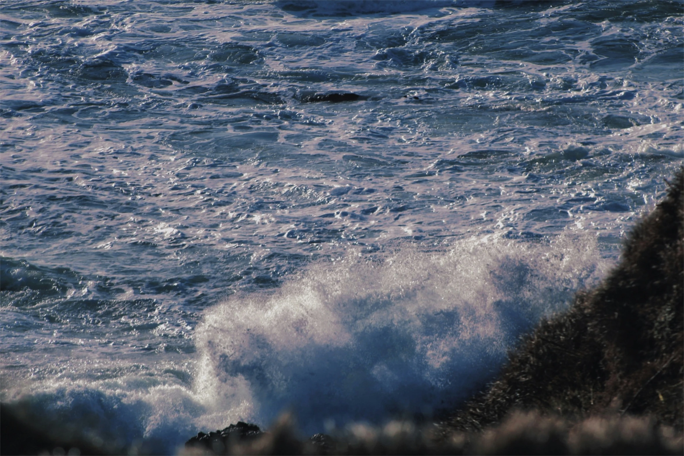 the blue wave is hitting on a rocky shore