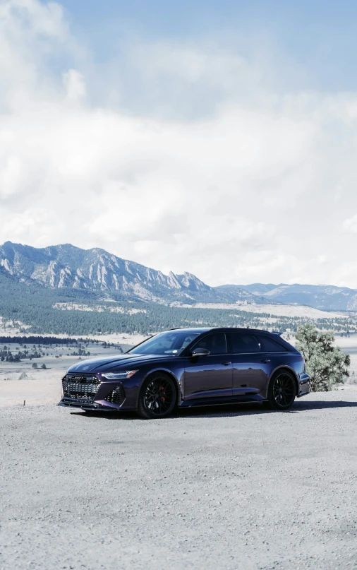 a grey car parked on the gravel in front of mountains