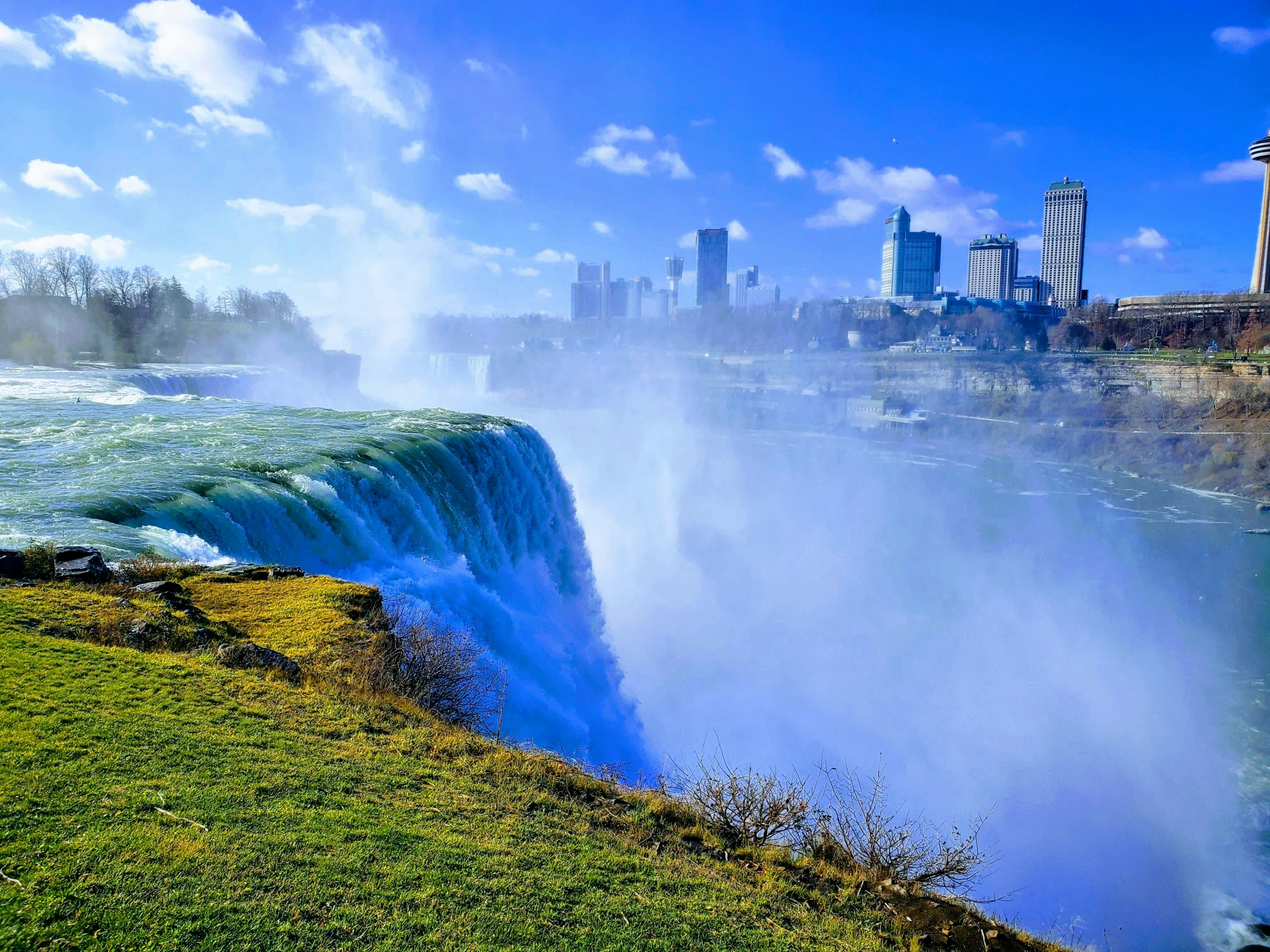 a waterfall is being pulled into the river with the city skyline in the background