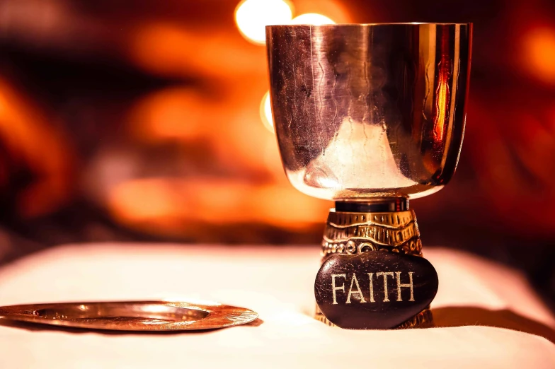 a small silver chalice next to a metal cup