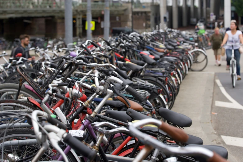 a row of bikes with people walking down the sidewalk