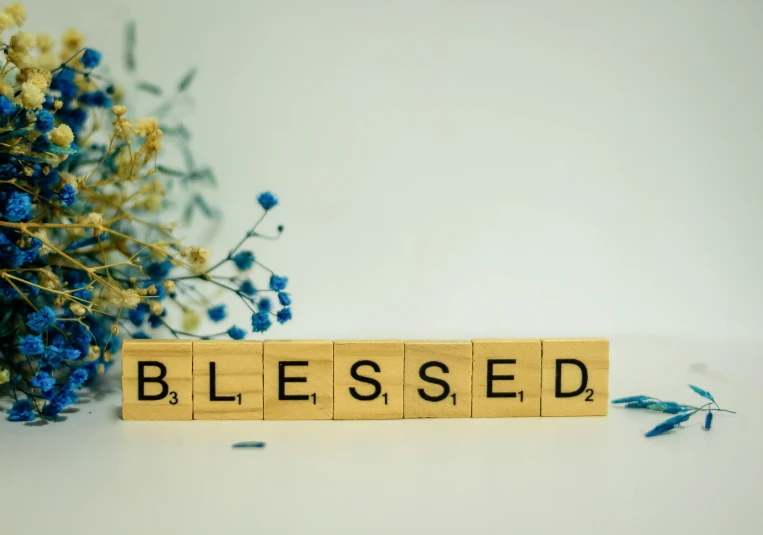 the word blessing written on wooden blocks sitting beside flowers