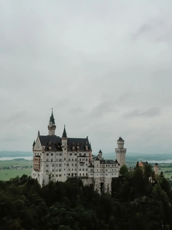 a castle on top of a hill surrounded by green trees