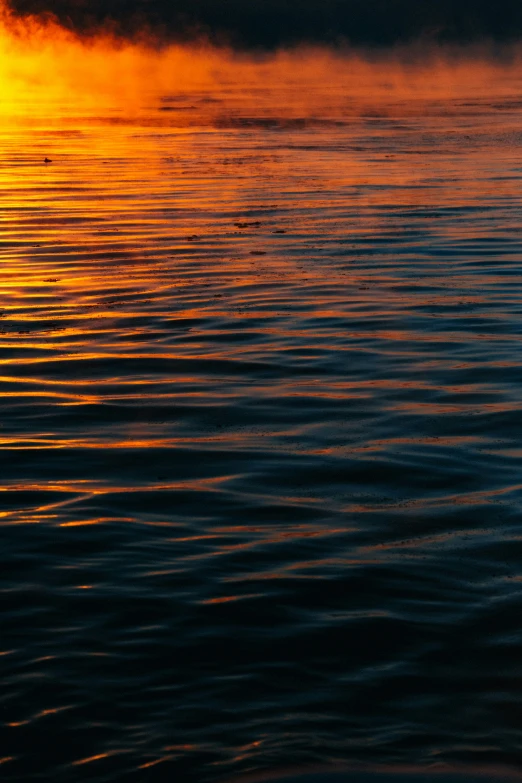 an orange and yellow sunset reflects in the still water