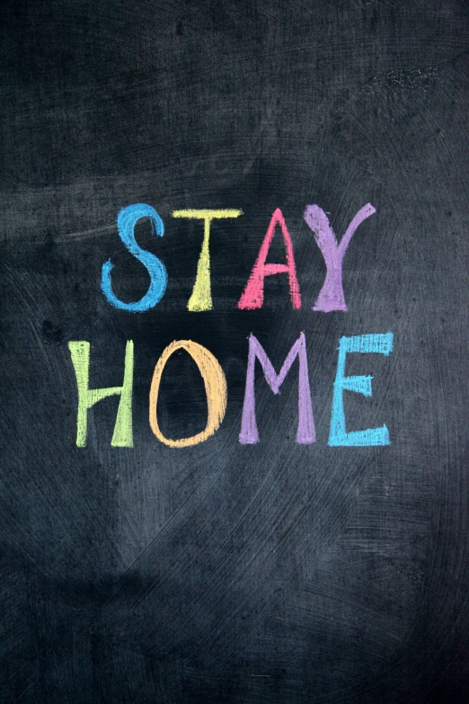 the word stay home written in colorful crayons on a blackboard