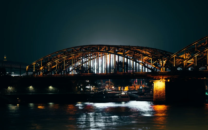 an illuminated bridge over water in the night time