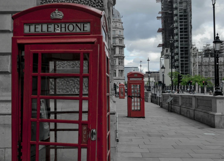 a group of red telephone booths sitting next to a street