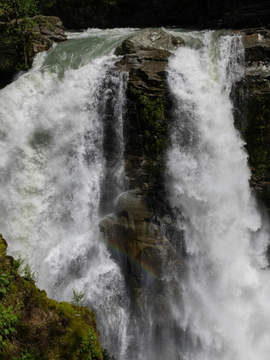 a large waterfall on the side of a mountain in autumn