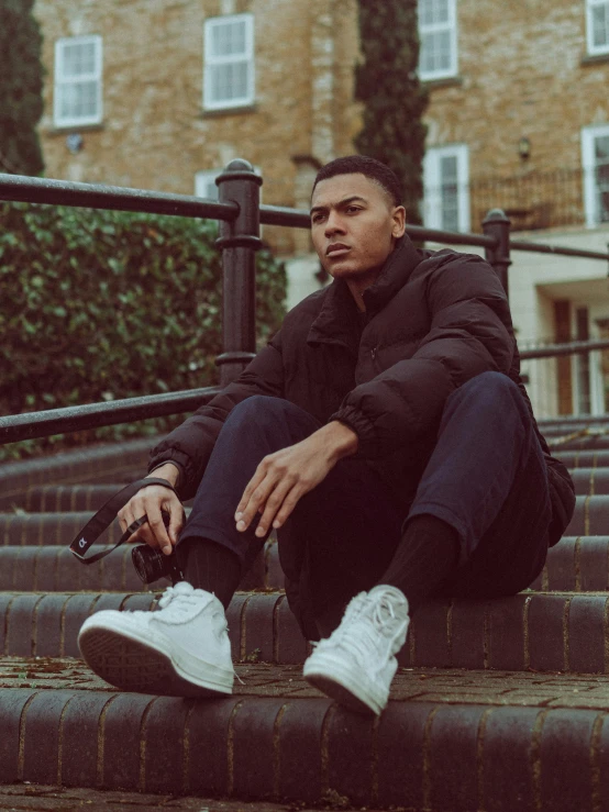 a young man sits on some stairs