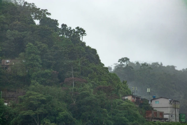 a hill with houses built on it and a rain shower is seen