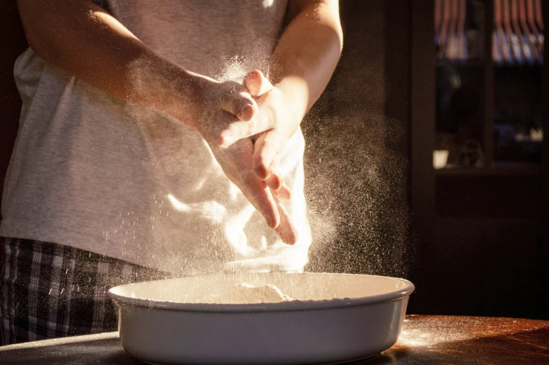 a person standing in front of a bowl with flour on the bottom of it