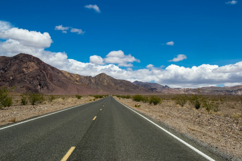 an empty stretch of road with the mountain in the background