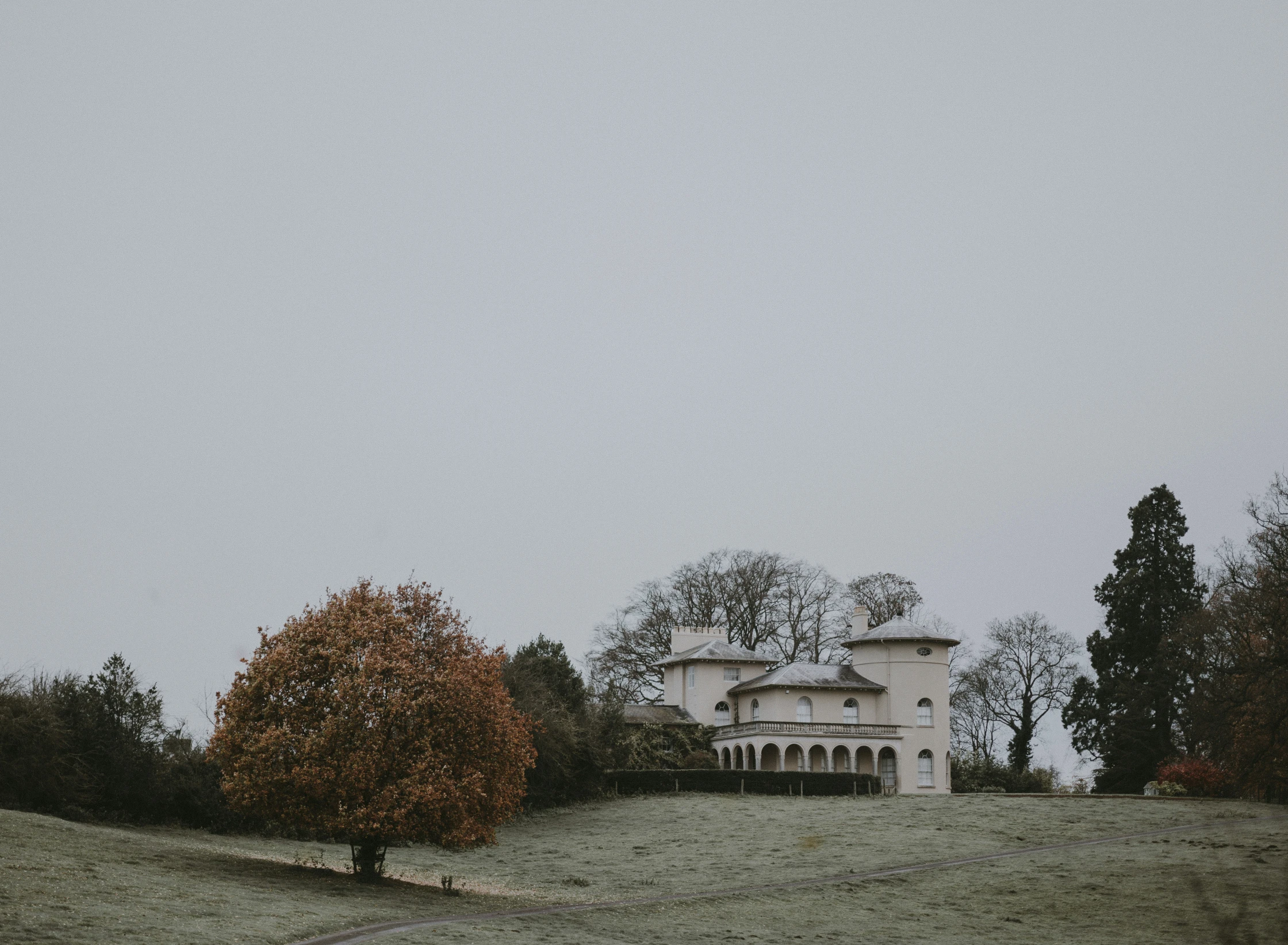 an old house on a hill with trees around it