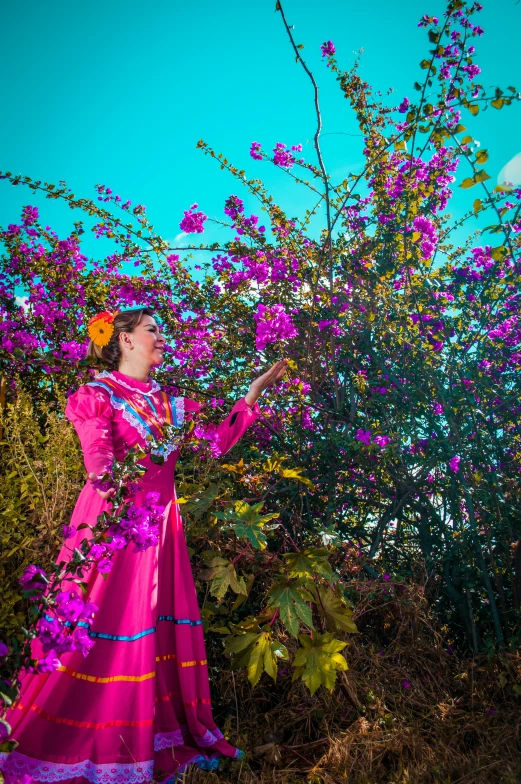 a woman in a long dress standing under a flowering tree