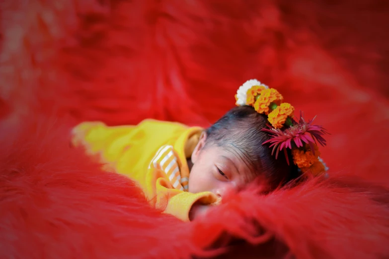 small baby is sleeping and wearing red feathers