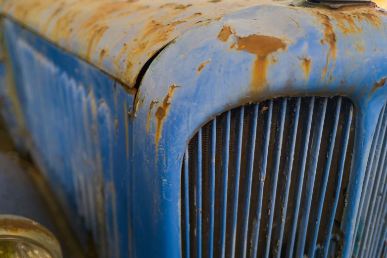 an old blue truck sits in the dirt