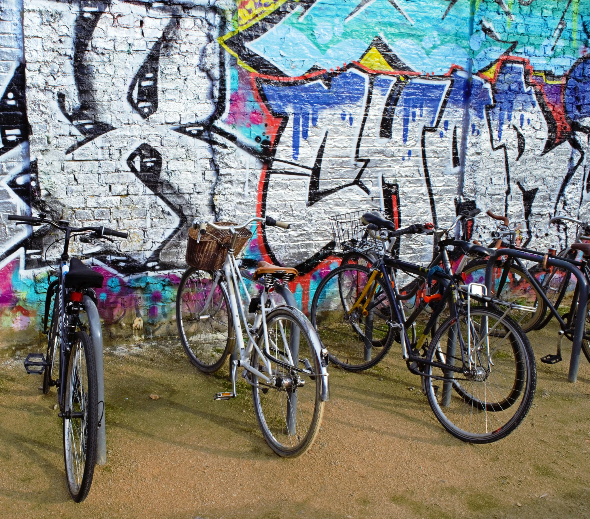 a row of bikes lined up against a wall covered in graffiti