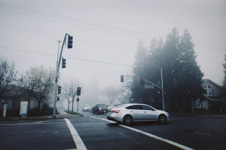 there is a very foggy intersection with some cars