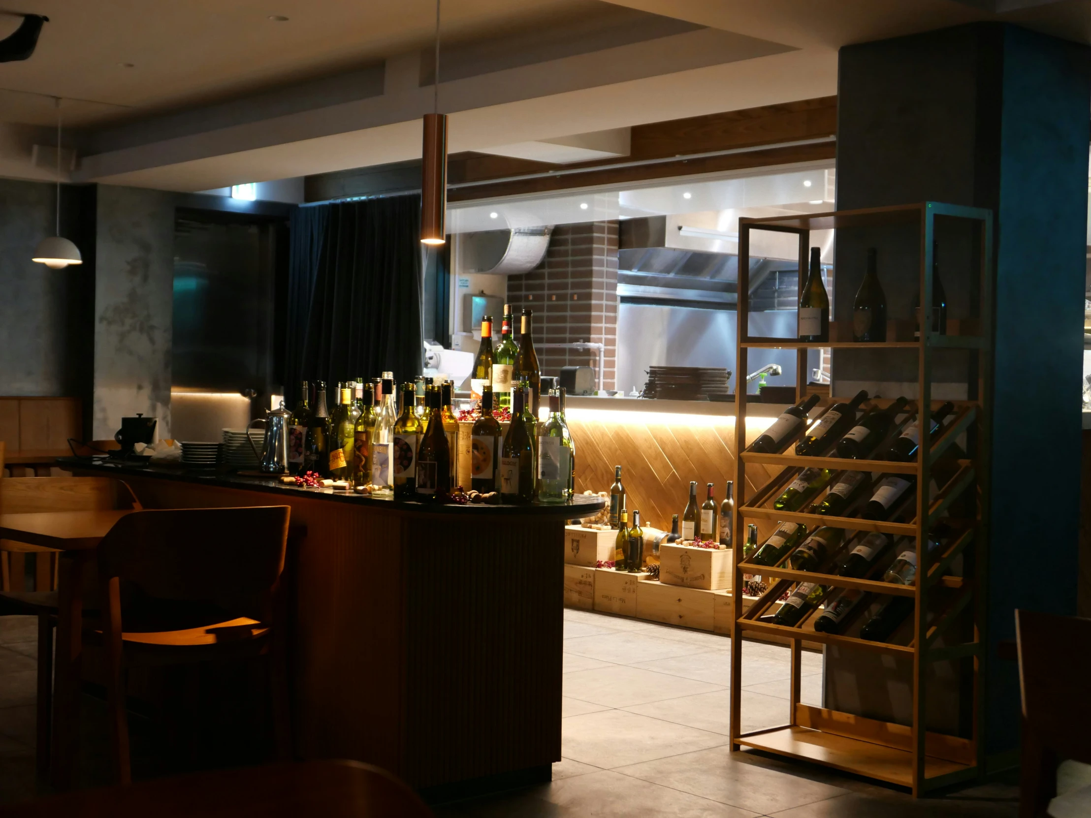 an open kitchen area with a counter with lots of bottles of wine