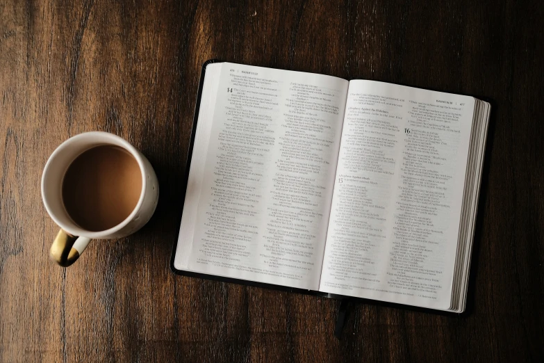 an open book with two pens and coffee cup