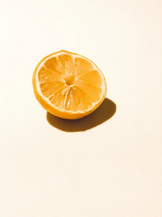 a lone orange sitting in the middle of a white surface