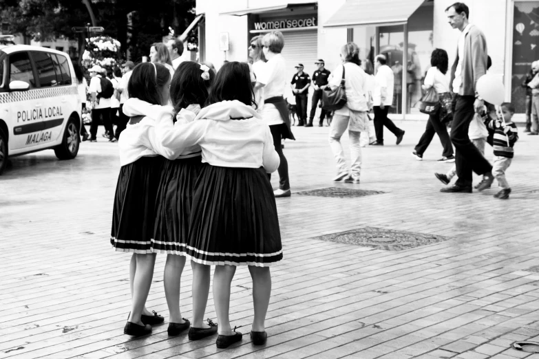 two girls are hugging and crossing the street