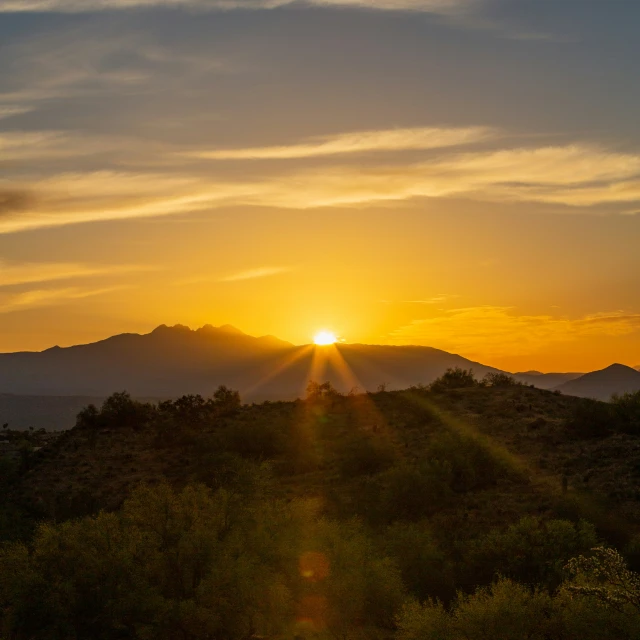 the sun sets in the distance over a small hill