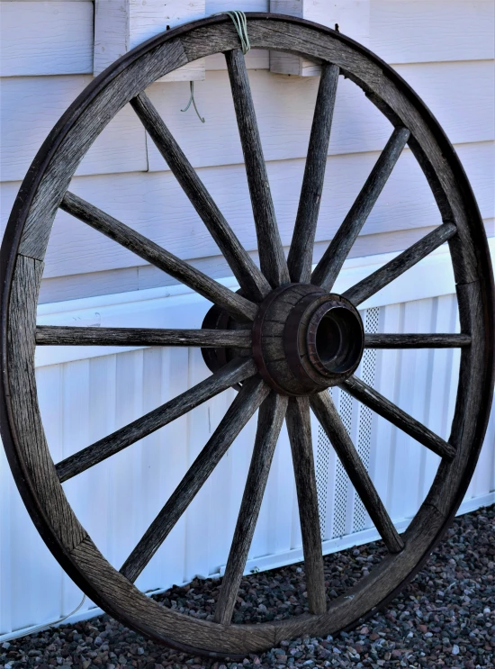 a wooden wheel is hanging outside a white building