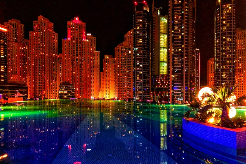 illuminated buildings surround a pool at night in a city