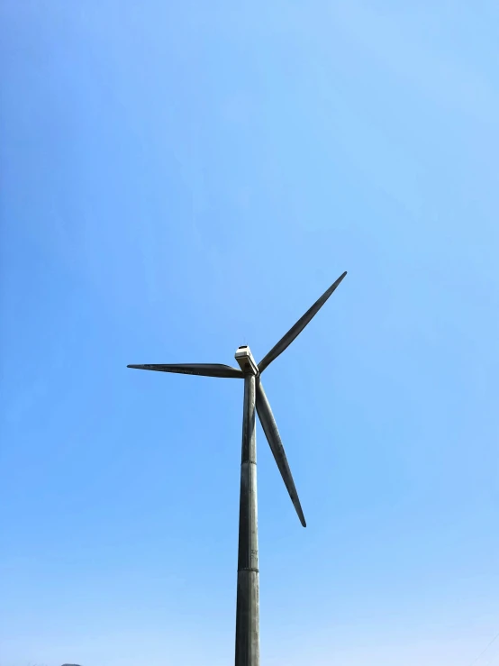 three wind turbines on top of a sandy beach