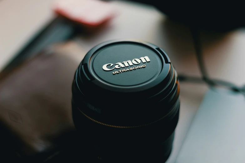 a canon camera lens cap sitting on top of a laptop