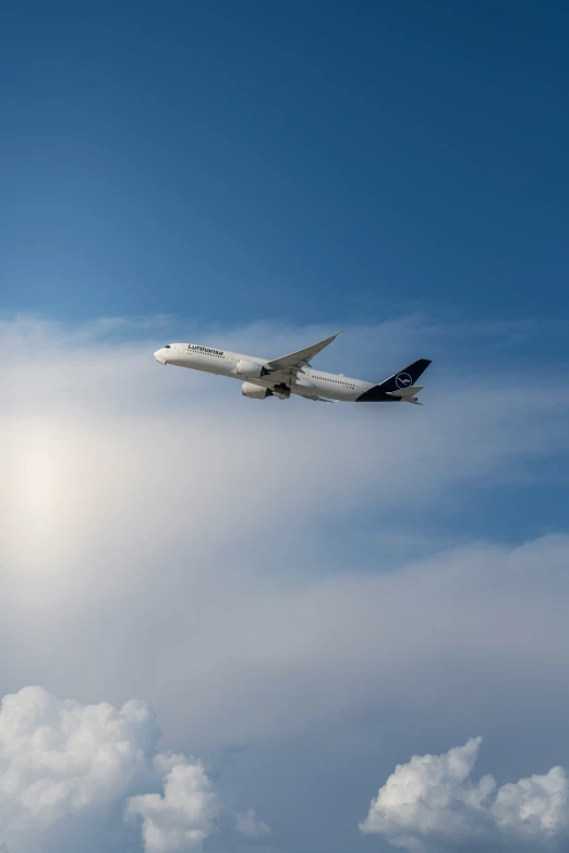 a plane flies through the sky, against a blue and white cloud