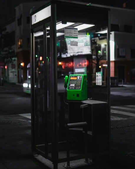 a green pay phone sitting in a bus stop