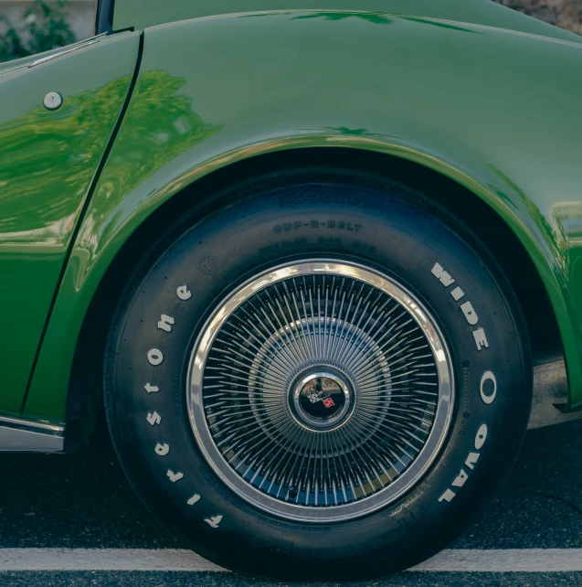 a green car parked in a lot with the wheel tire cap painted black