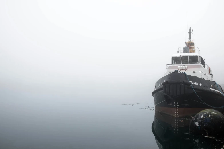 a small boat floating through the fog on the water