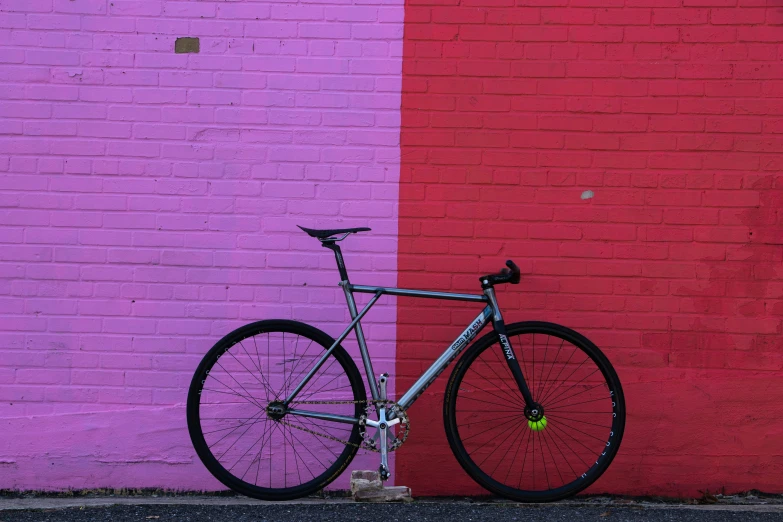 a bicycle is leaning against a pink and red wall