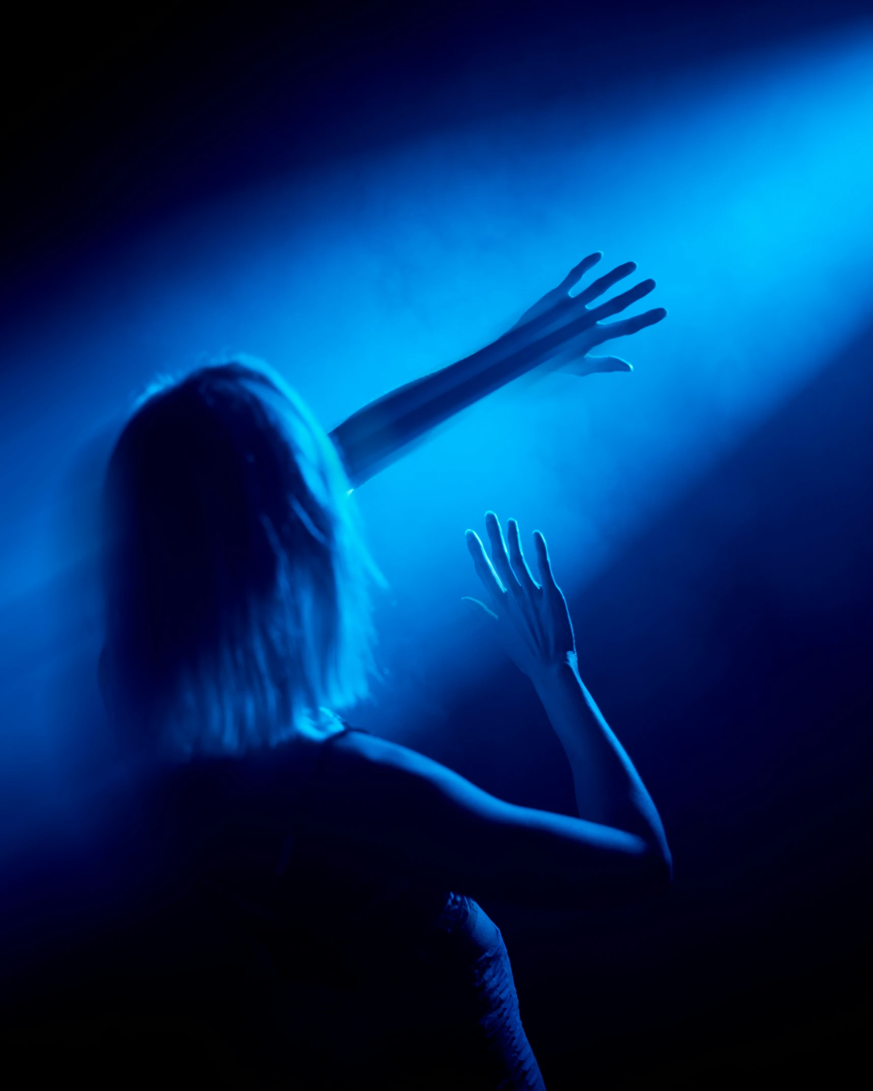 a female is reaching out from behind a dark background