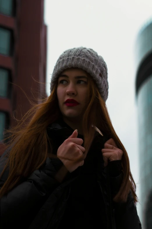 a woman is holding her hair while wearing a hat