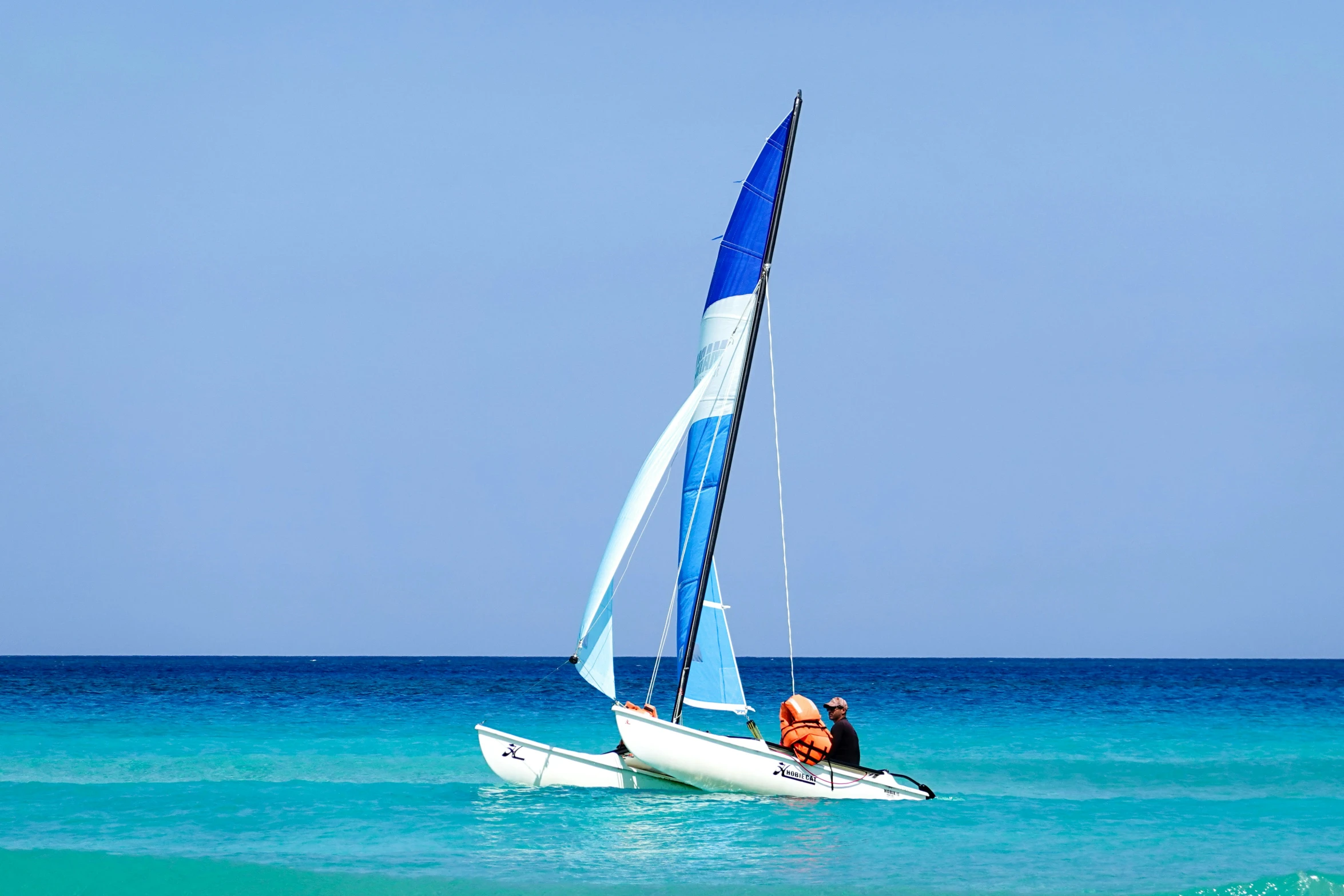 a man riding on the back of a sailboat