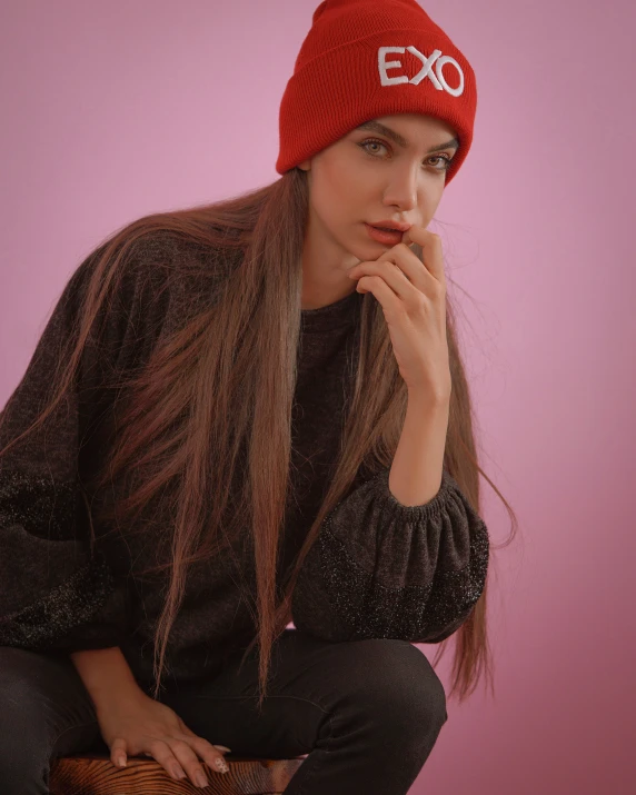 the young woman has long hair and wears a red knit beanie