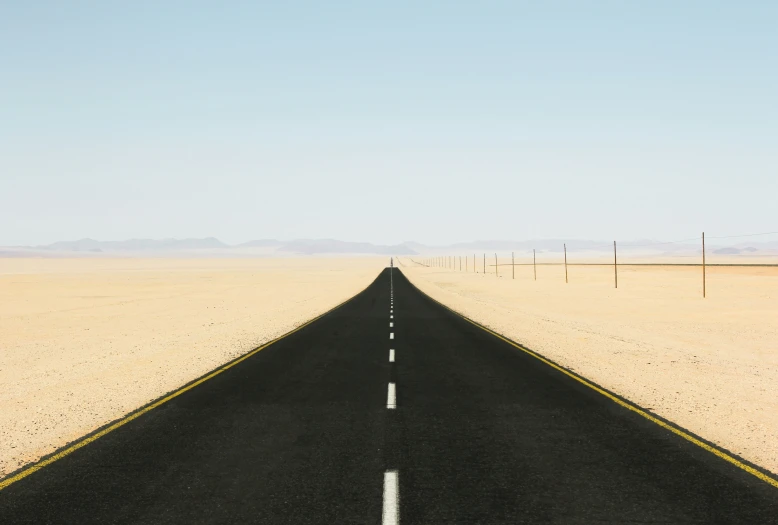 the road goes through an empty desert landscape