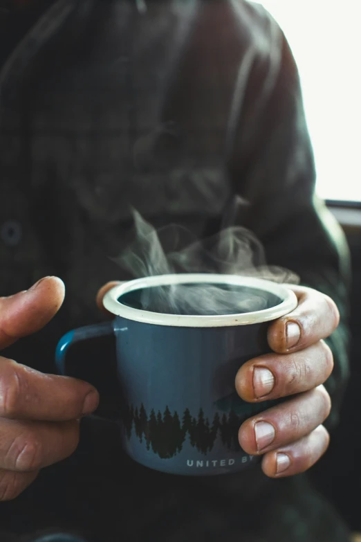 a person holding a coffee cup with steam rising from it