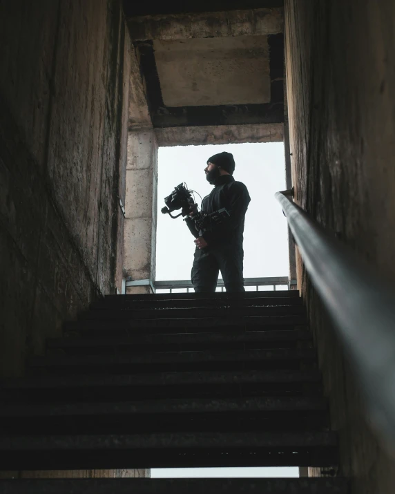 man standing on steps holding camera with light coming in from behind