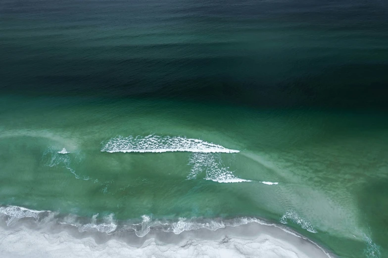 a large body of water with waves and white sand