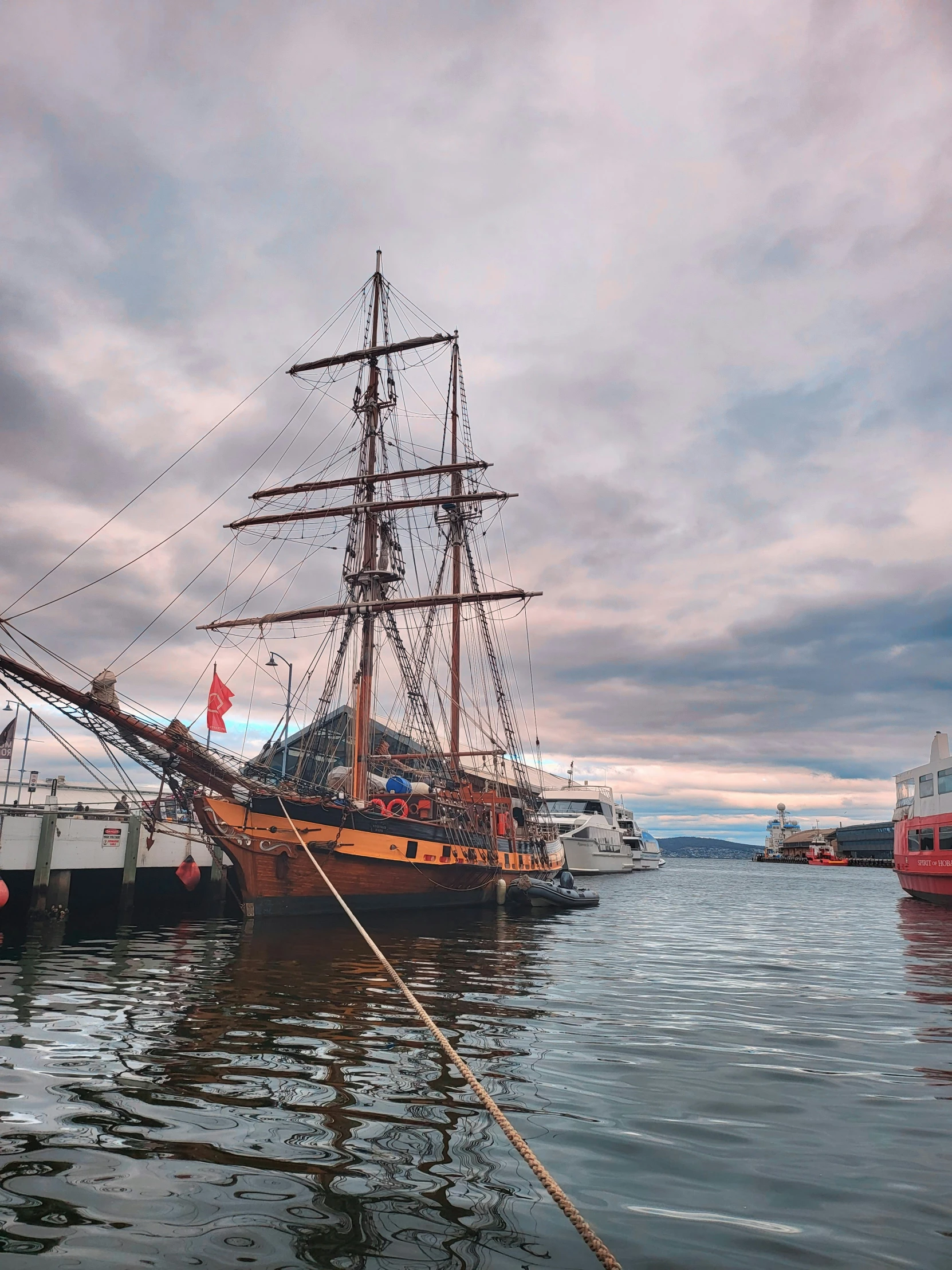 several boats parked in the harbor and one without sails