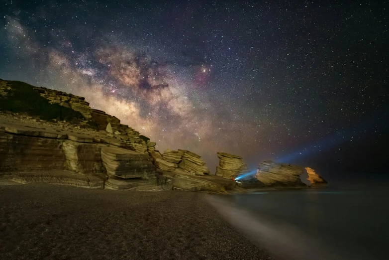 a long exposure pograph of the stars above an ocean shore