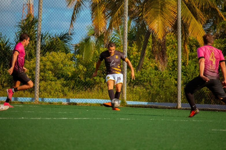 three people on opposite teams playing soccer and running