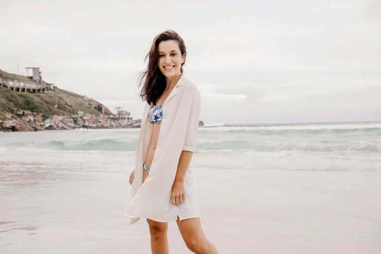 a beautiful young woman standing in front of the ocean