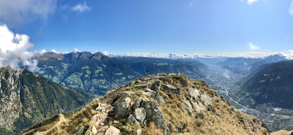 a man sitting on the edge of a mountain looking at a valley